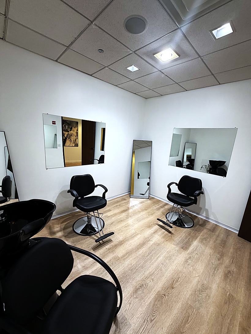 A salon suite with two styling chairs, wall mirrors and its own shampoo bowl