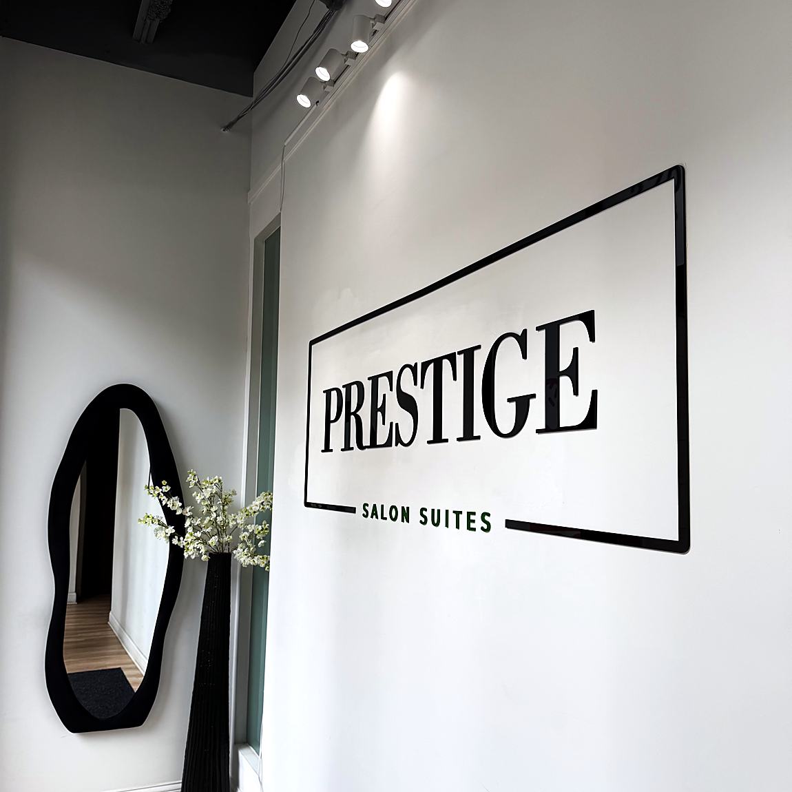 The entry at Prestige Salon Suites, with the Prestige wall sign and a black arched mirror